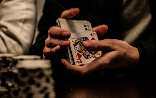 A player shuffling a deck of cards with some poker chips on the table.